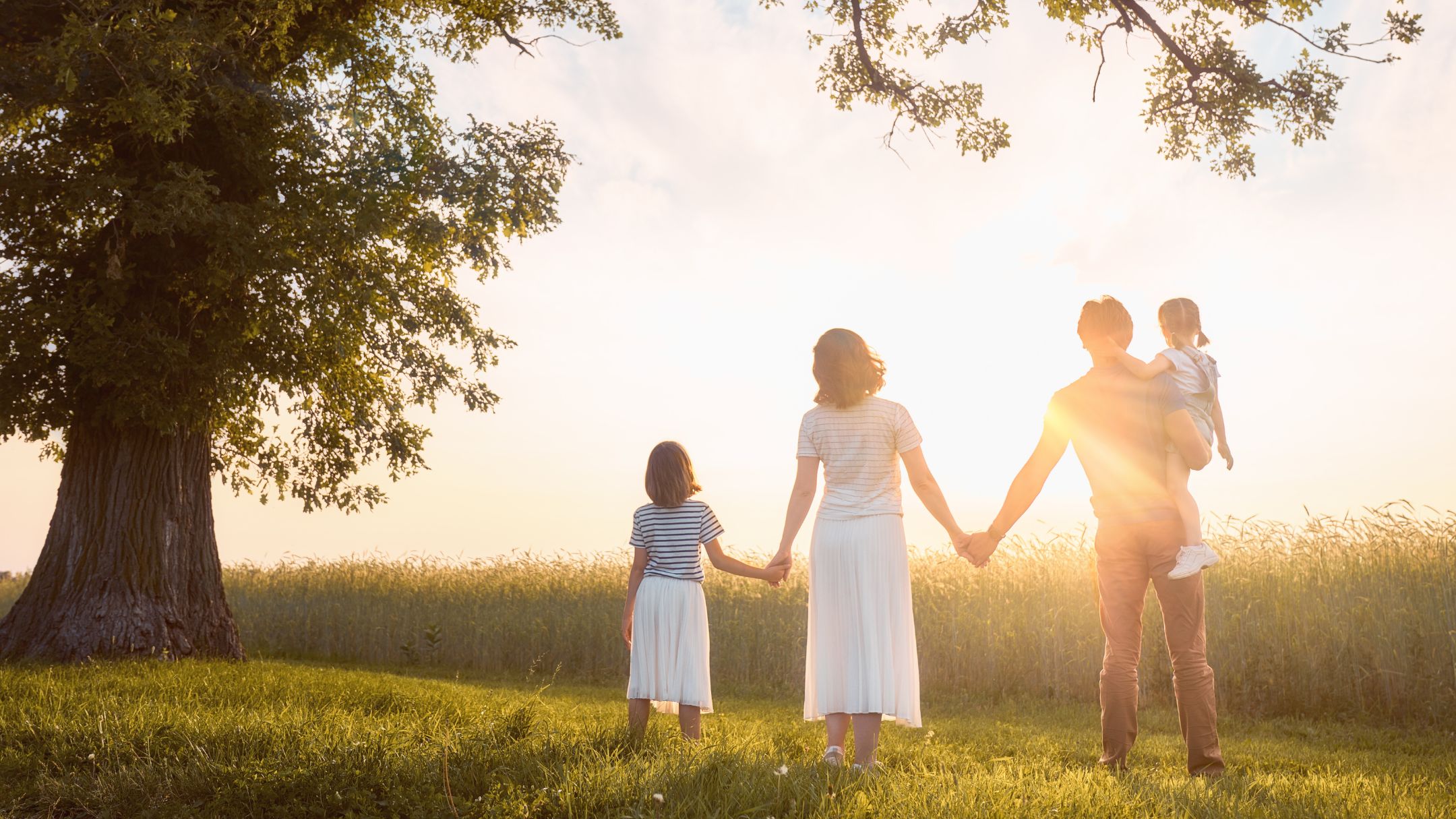 Una familia de la mano mira el horizonte en el campo